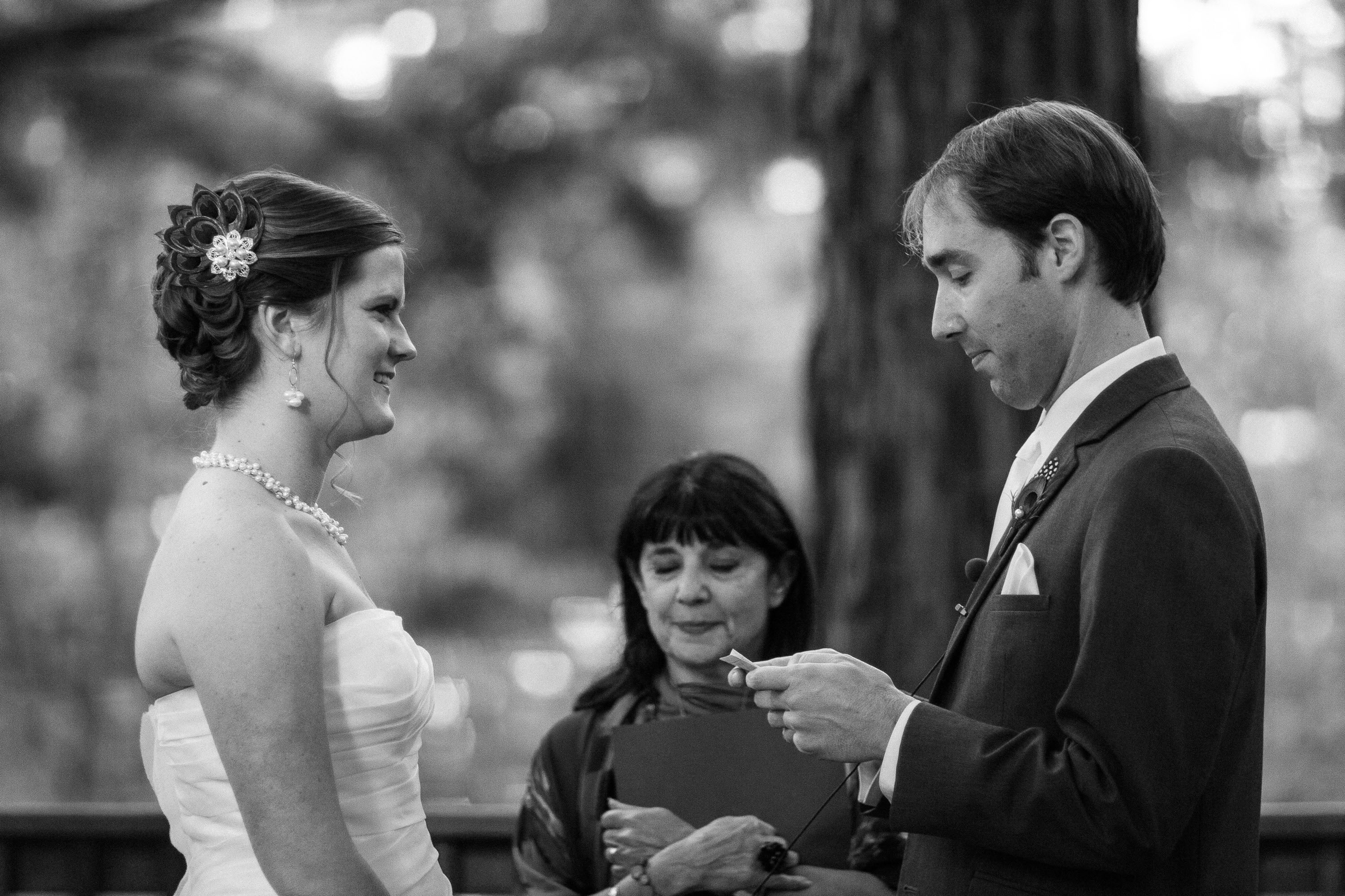 The groom reads one of his wedding vows while the bride looks on with love, at Pema Osel Ling in the Santa Cruz mountains