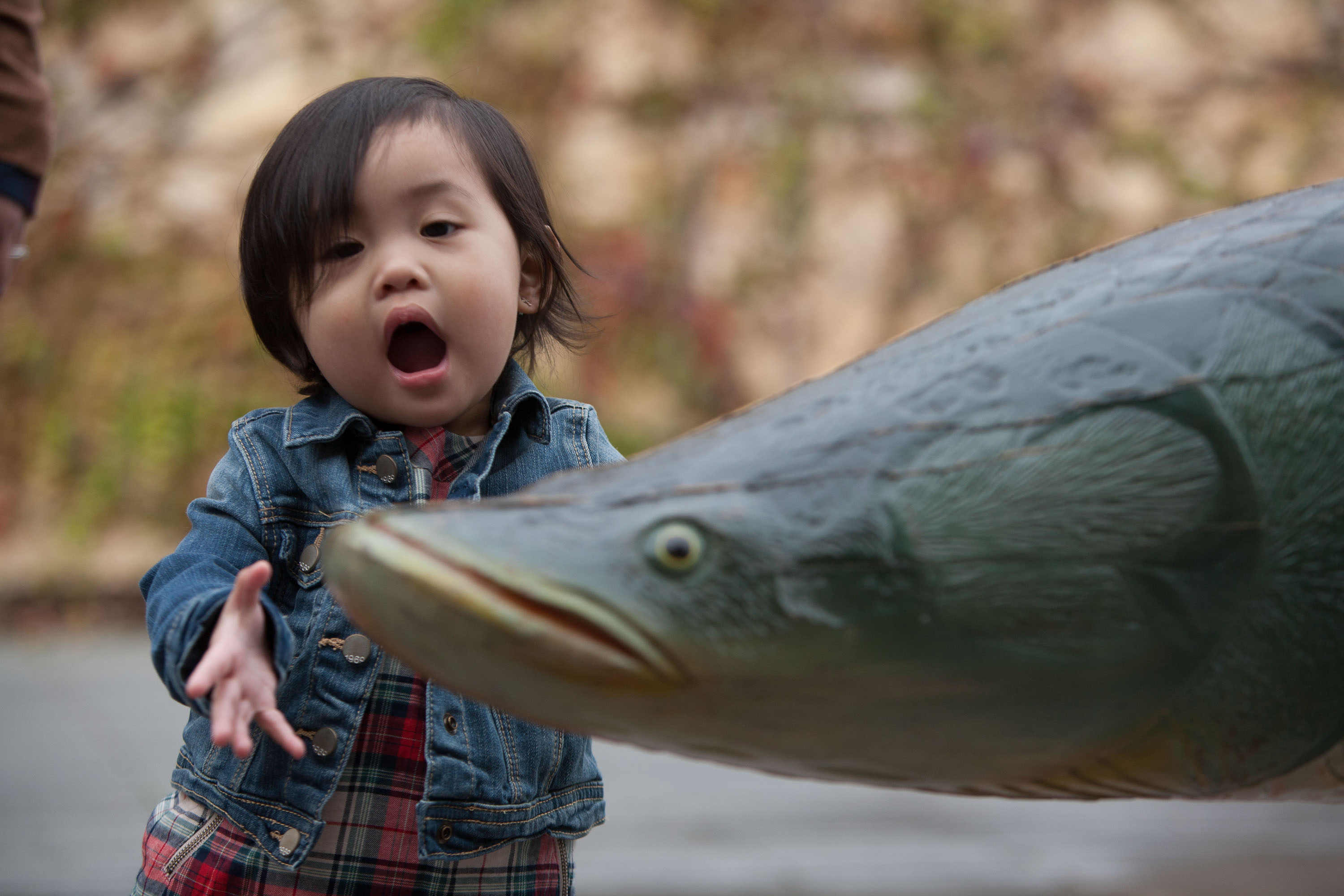An adorable little girl makes a fish face while playing with a wooden fish.