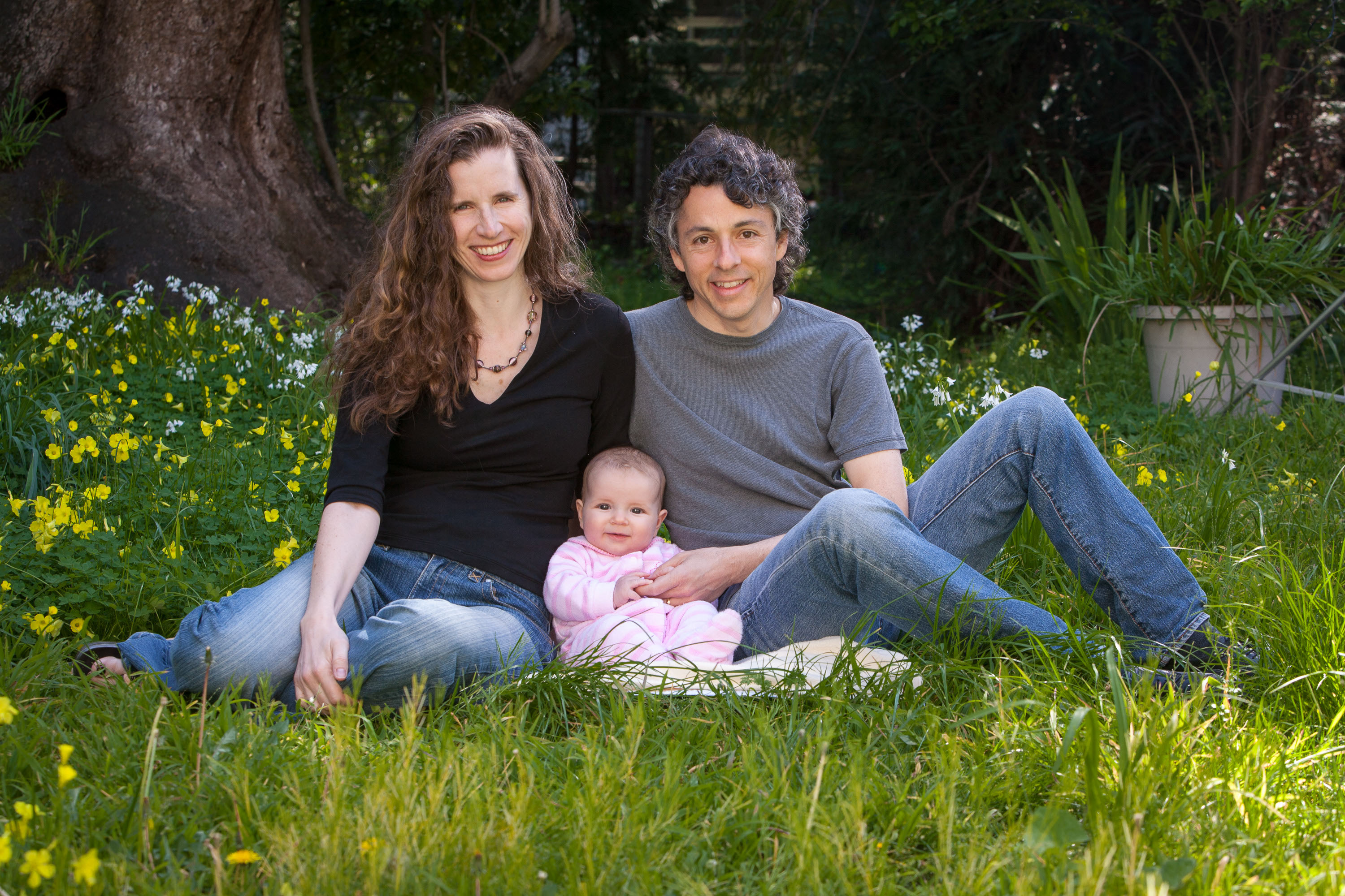 A Berkeley couple poses with their baby in their back yard.