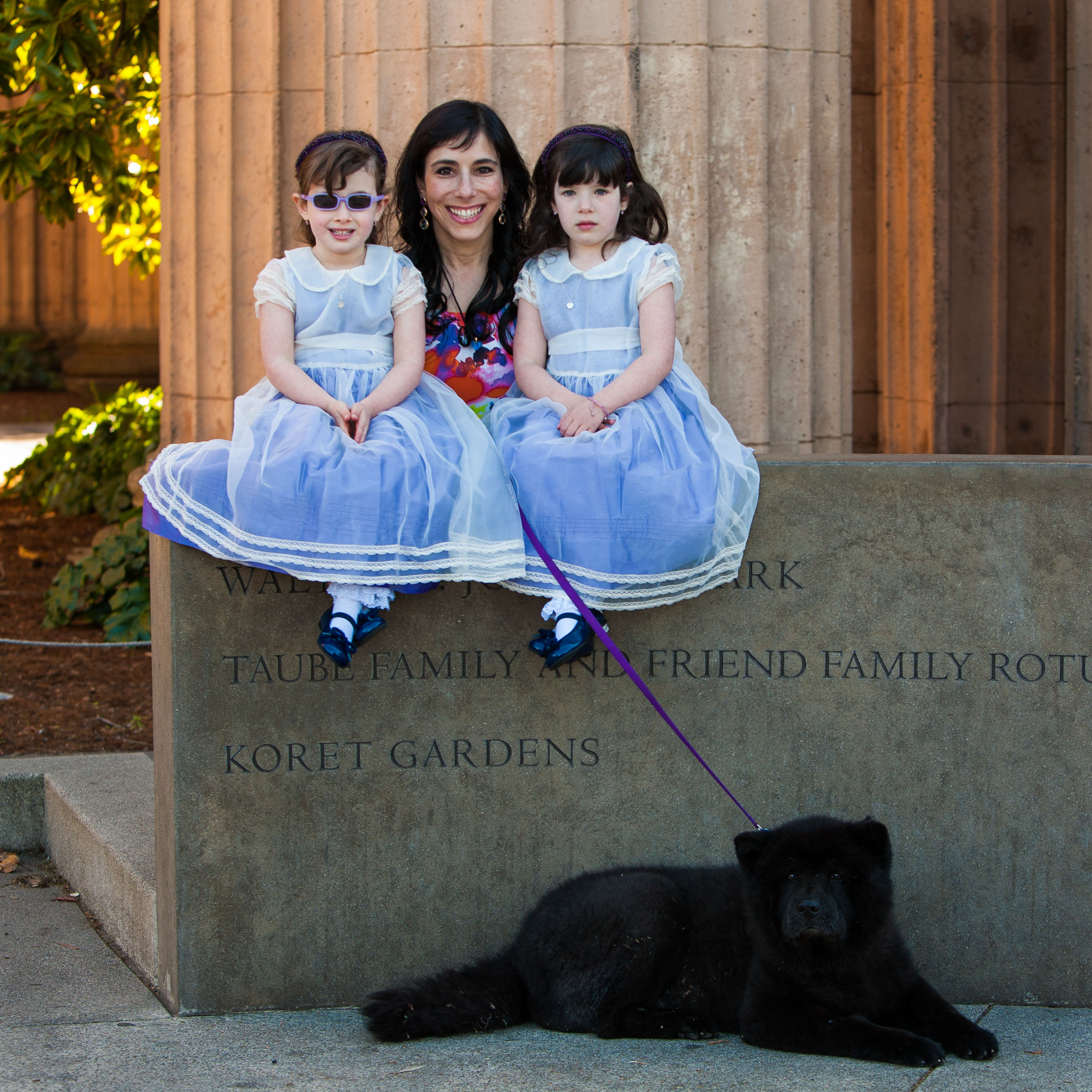A mom and her twin daughters with their beautiful black Husky at the Palace of Fine Arts.
