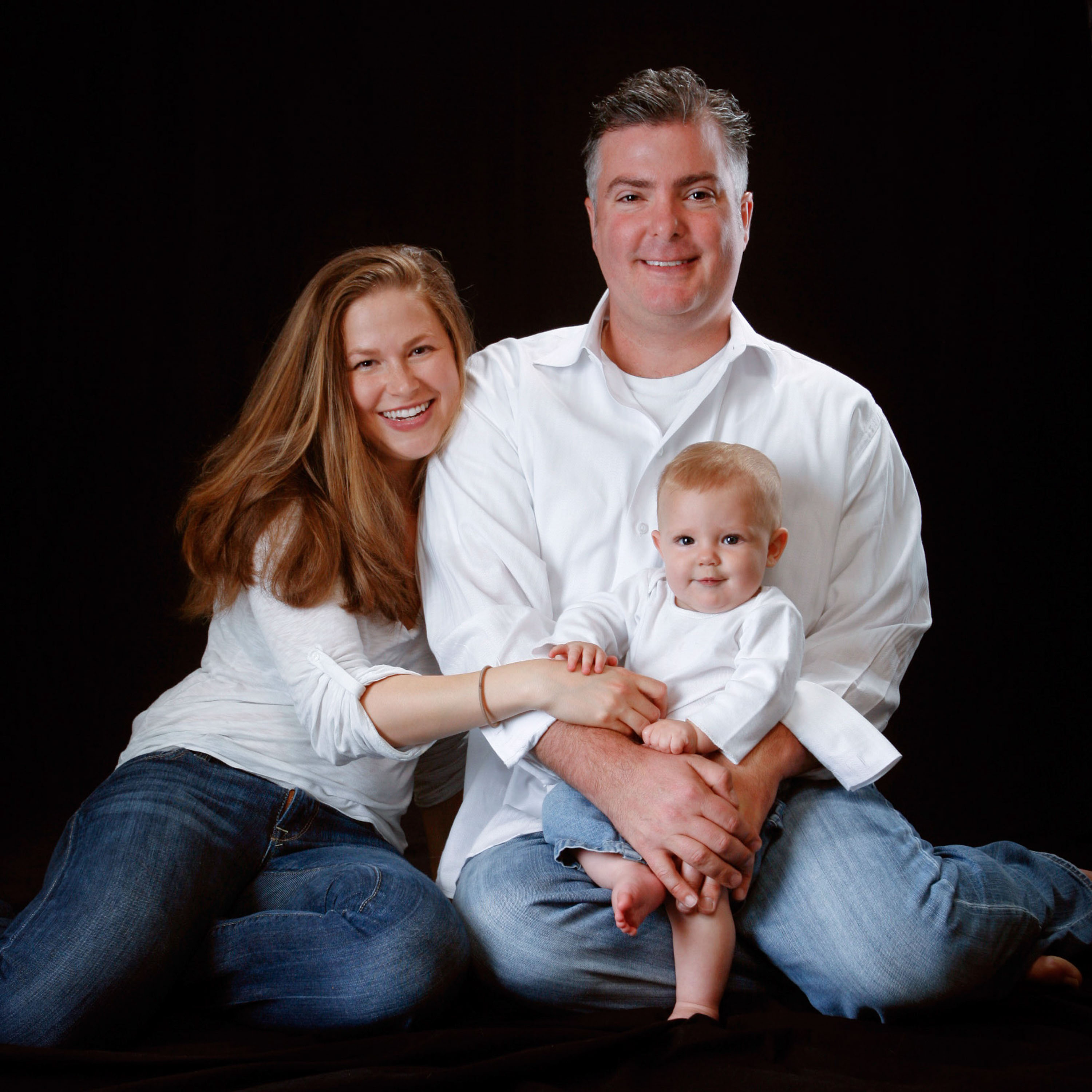 A couple in a relaxed pose with their new baby in this studio portrait made by San Francisco portrait photographer Checkerbox Photography.