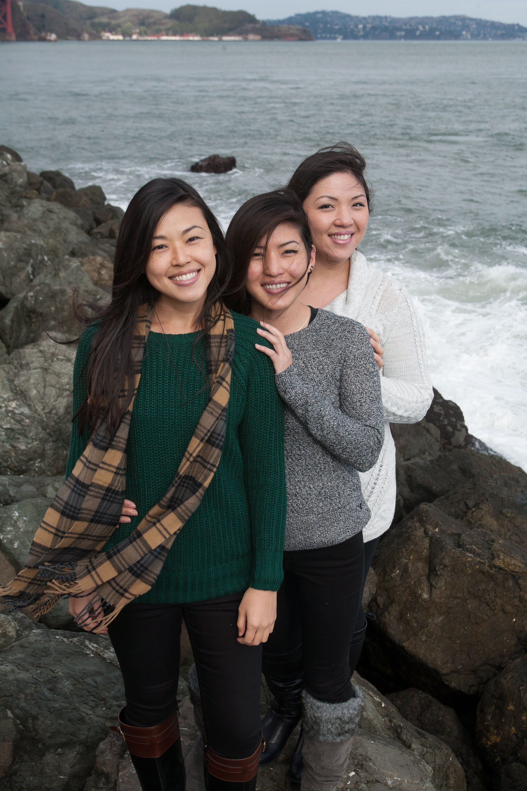 Three Asian sisters on the rocks at Fort Point.