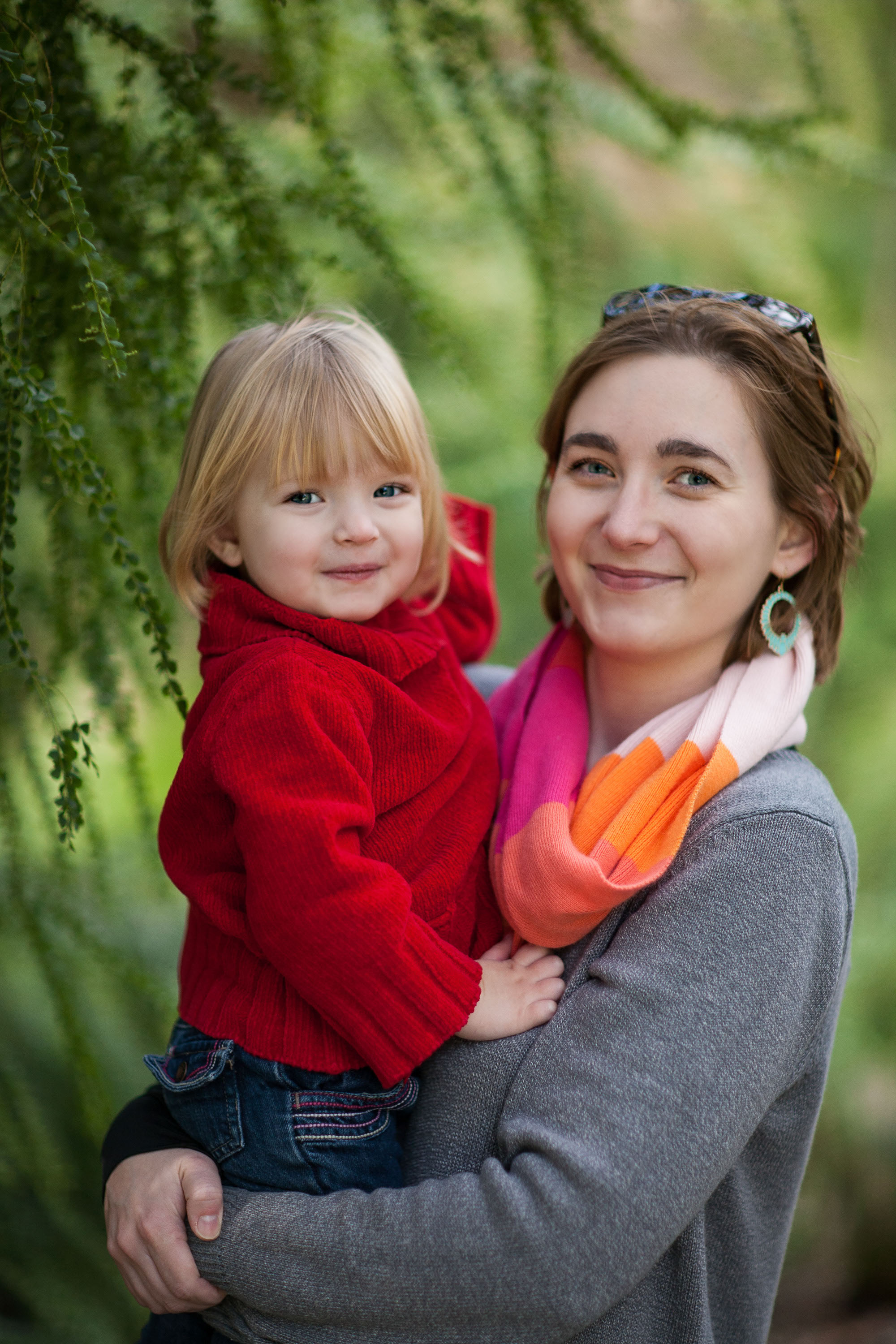 A mom holds her daughter amid the lush greenery of the San Francisco Botanical Garden.