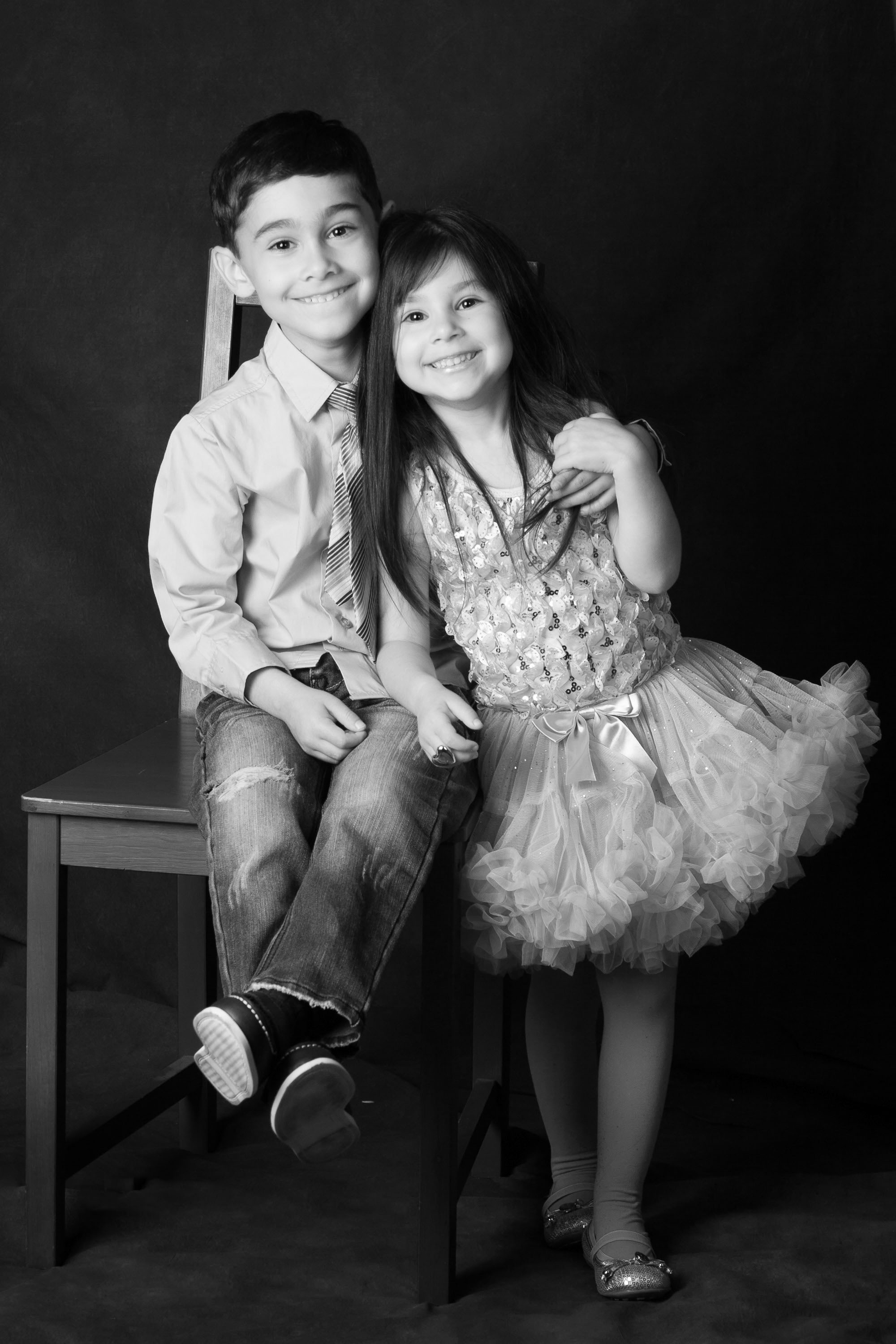A sparkling black and white studio portrait of young brother and sister