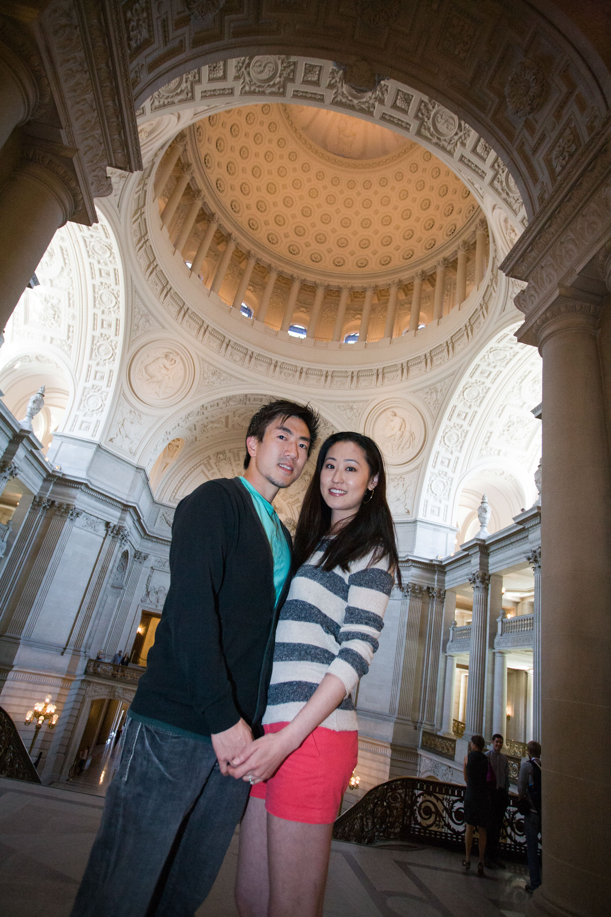 A couple framed by the dramatic interior rotunda at San Francisco City Hall