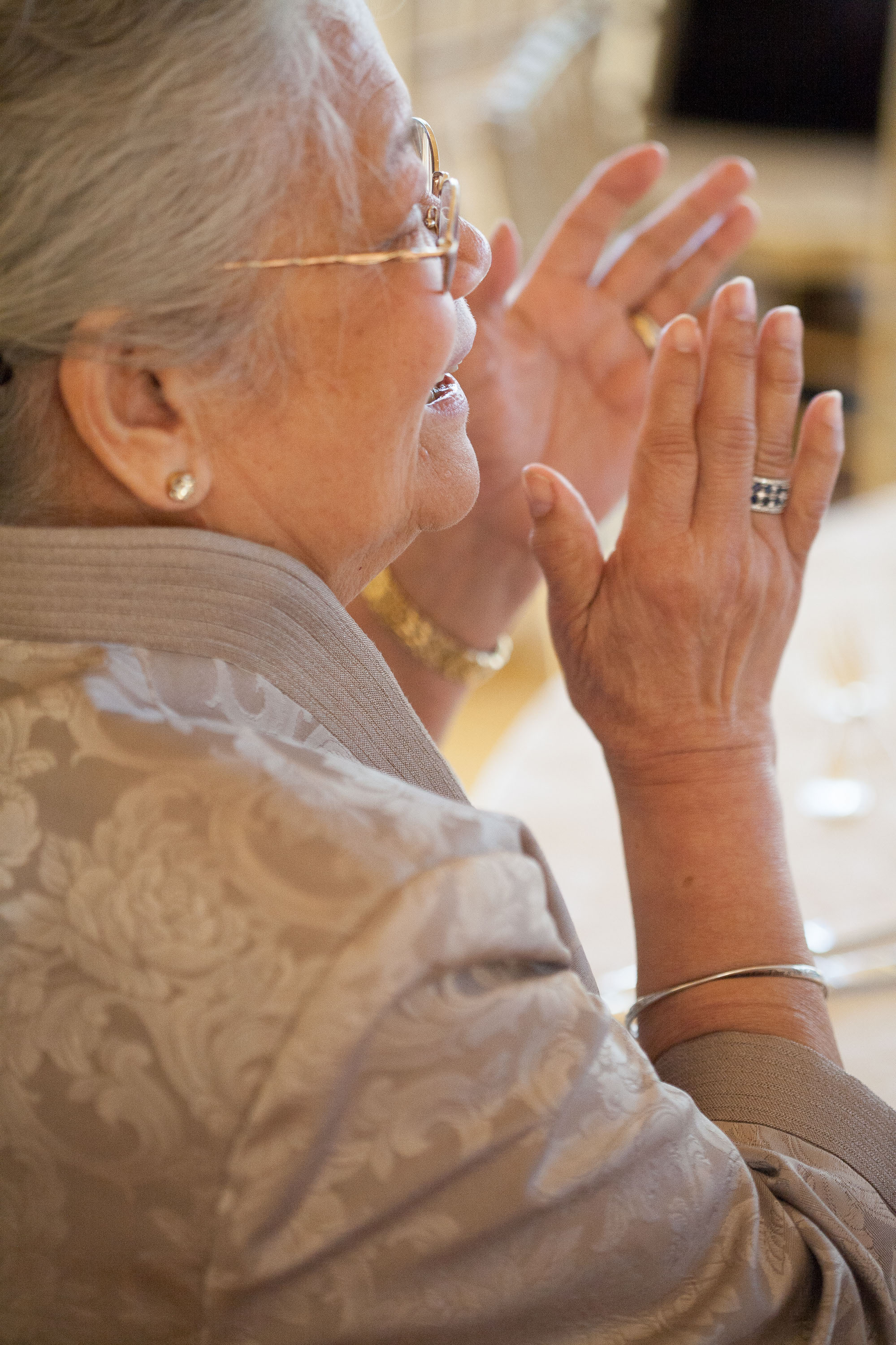 An elderly Filipino woman applauds as the bride and groom make their entrance