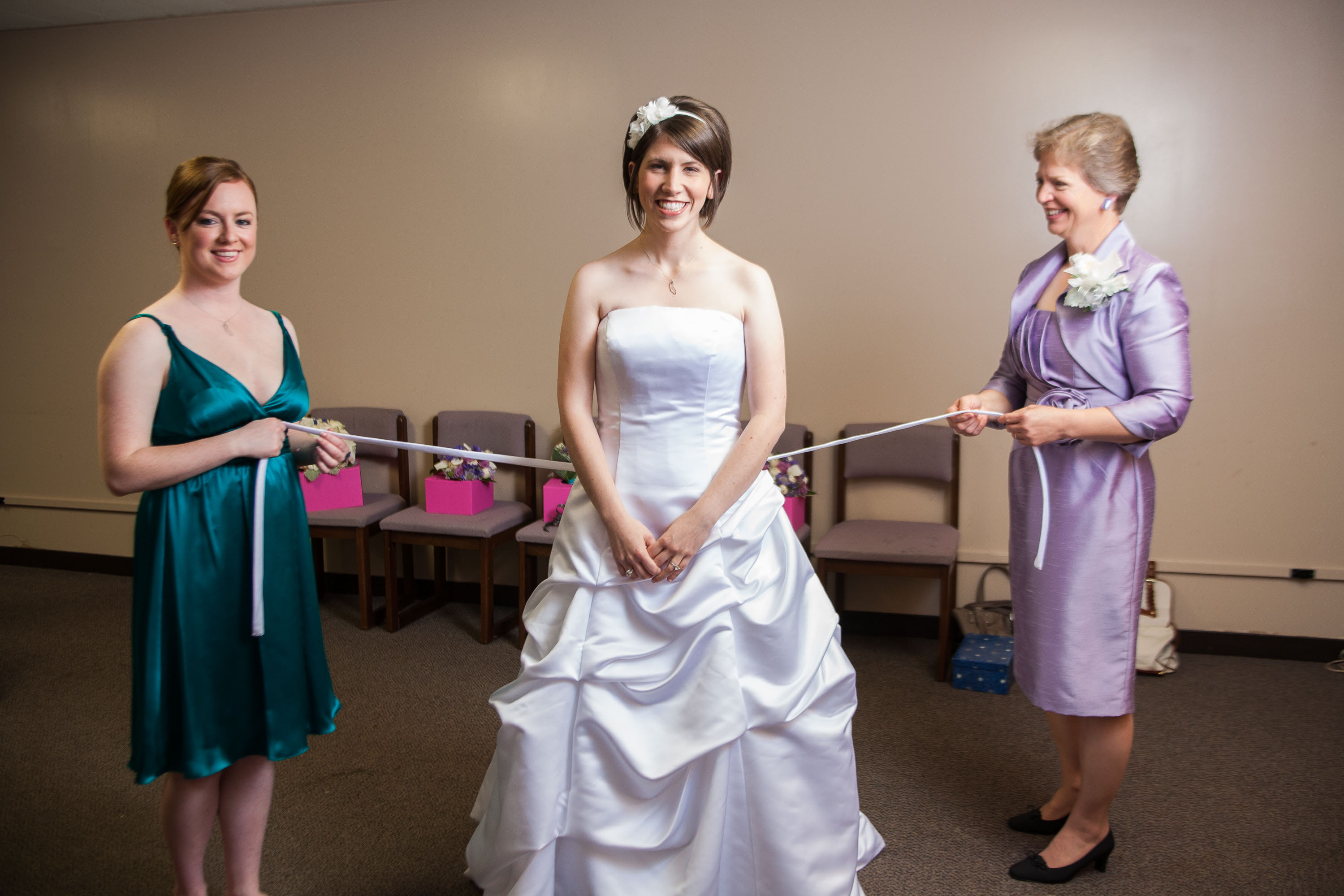 The maid of honor and the mother of the bride get ready to lace up the bride's dress,  at St. Mary's Cathedral in San Francisco.
